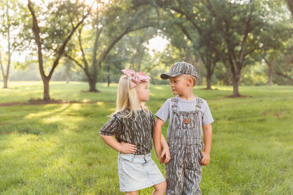 bc raskulls toddler camo apparel boy in camo cap and twill overalls with girl in camo t-shirt