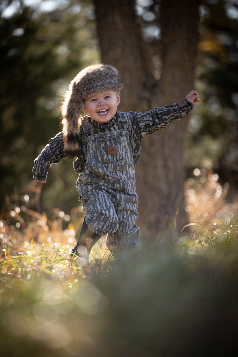 toddler playing in bc raskulls camo twill overalls and long sleeve shirt